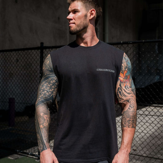 A muscular man with tattooed arms wearing a black sleeveless tank top from Zombie Labs, standing outdoors next to a chain-link fence.